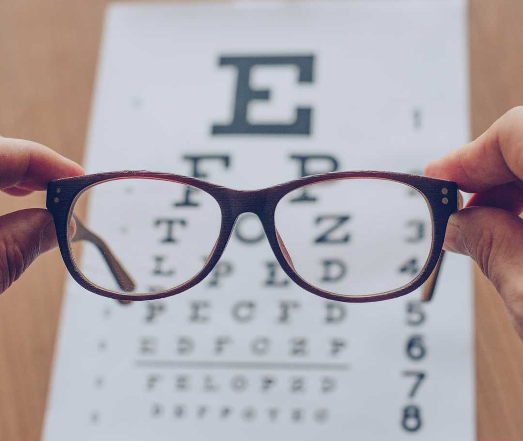 Das Bild zeigt einen Blick durch eine Brille auf einen Sehtest mit unterschiedlich großen Buchstaben