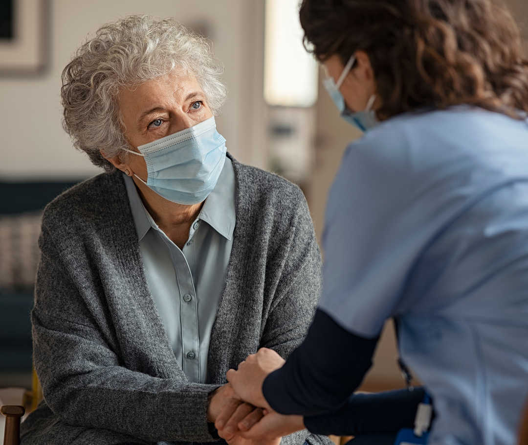 Eine Medizinerin spricht einer älteren Patientin Mut zu