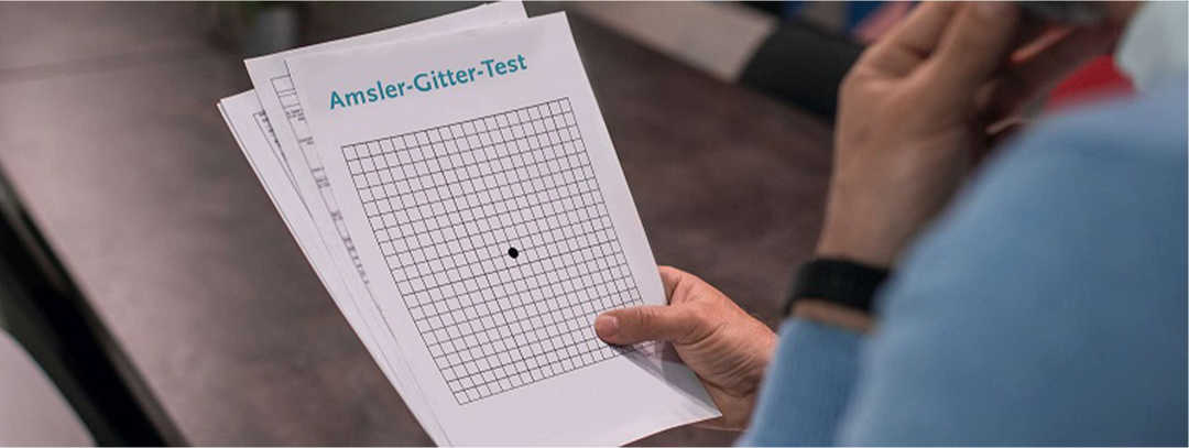 Ratgeber Makula: EIne Frau testet ihr Sehvermögen mithilfe des Amlser-Gitters EIne Frau testet ihr Sehvermögen mithilfe des Amlser-Gitters. Dabei handelt es sich um ein Blatt kariertes Papier mit einem schwarzen Punkt in der Mitte.Ka