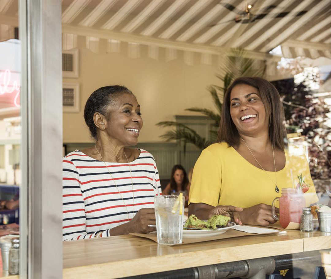 Zwei Frauen in einem Café unterhalten sich. Beide lachen.